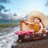 Little baby girl in big sun hat sitting into retro suitcase at the sea coast